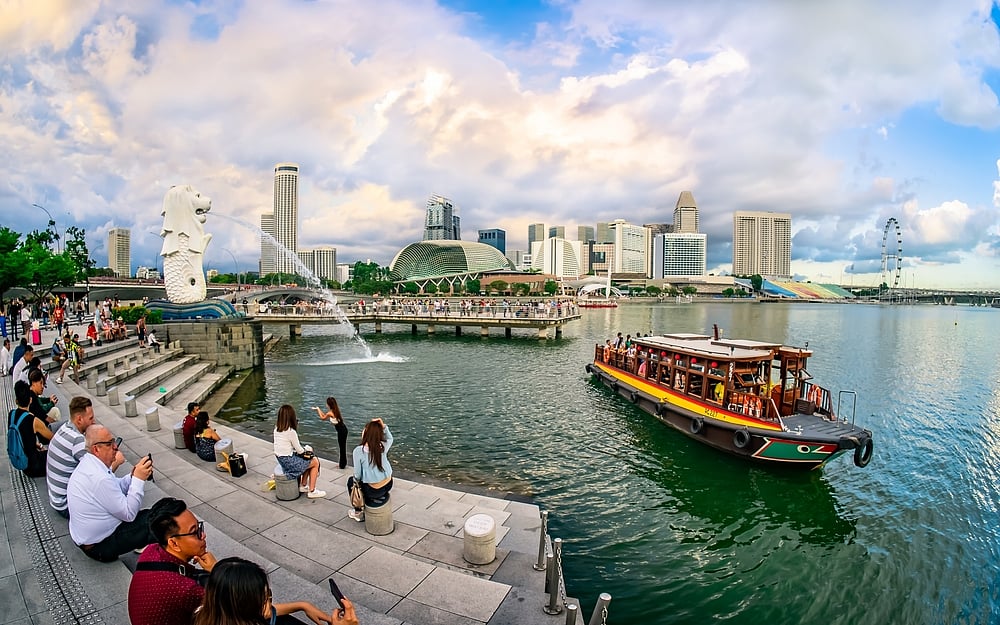 Bum Boat cruising with Merlion and Marina Bay skyline in the background